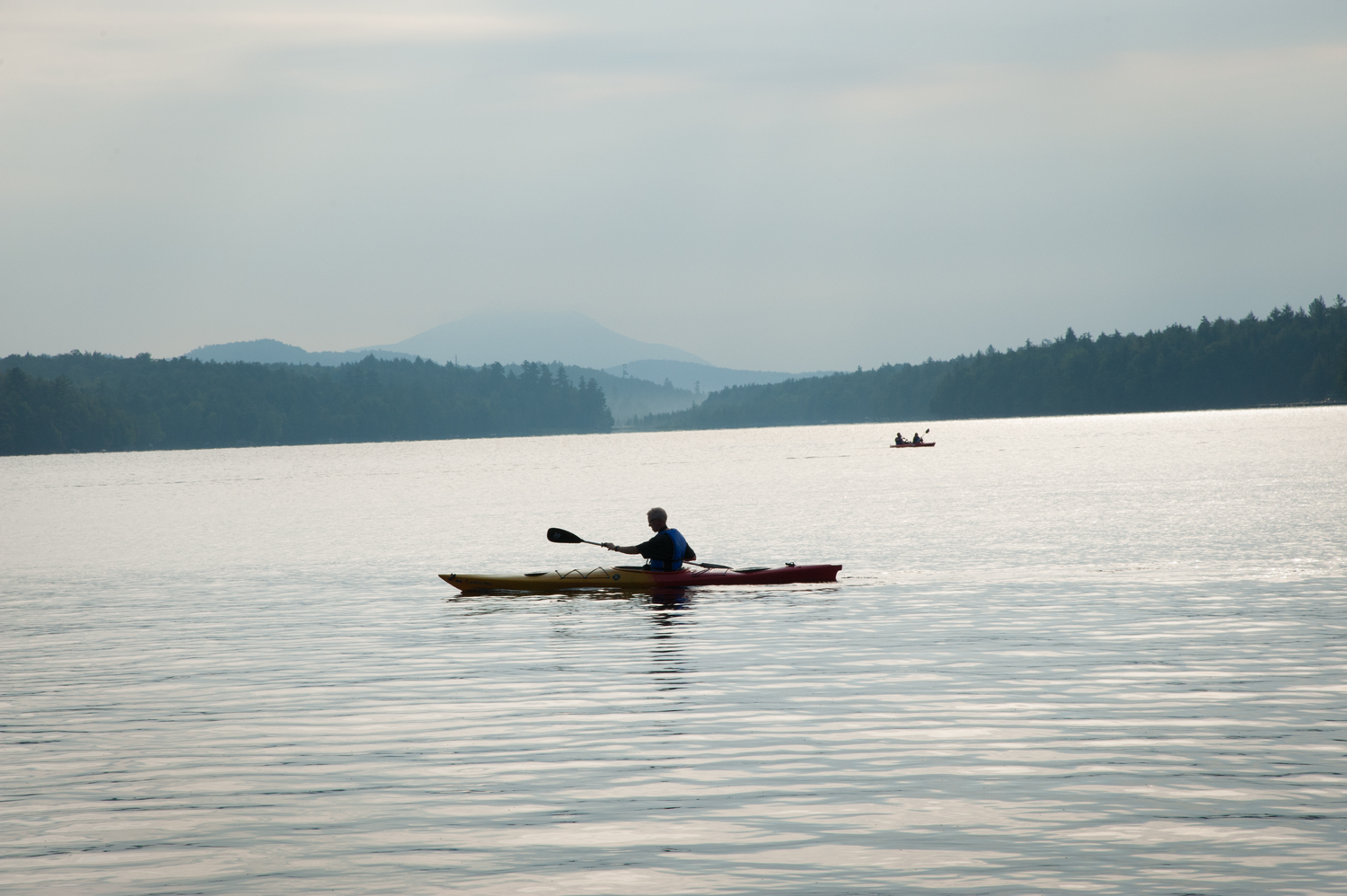 Kayaker on Raquette Lake with Blue Mountain in the background